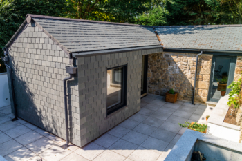 Photograph of a barn conversion featuring a slate hung extension and restored stone-work to a high quality finish.